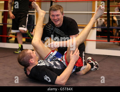 Der ehemalige Boxer Ricky Hatton (rechts) lacht, als er während einer Trainingseinheit bei Hatton Health and Fitness in Hyde, Manchester, von einem Zug namens The Triangle des britischen UFC-Kämpfers Paul Sass befreit wird. Stockfoto