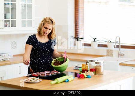 Schöne schwangere Frau Vorbereitung Muffins in Küche Stockfoto