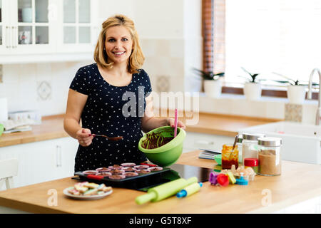 Schöne schwangere Frau Vorbereitung Muffins in Küche Stockfoto