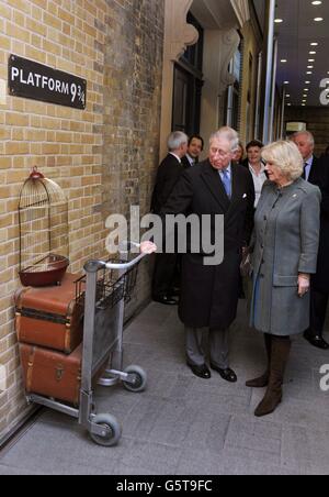 Der Prinz von Wales und die Herzogin von Cornwall versuchen, an Bord des Harry Potter inspirierten Hogwarts Express, auf der fiktiven Plattform der 9 und drei Quater, während einer Tour mit dem Prinz von Wales um den renovierten King's Cross Bahnhof, Bei einem Besuch des Terminals im Zentrum von London. Stockfoto