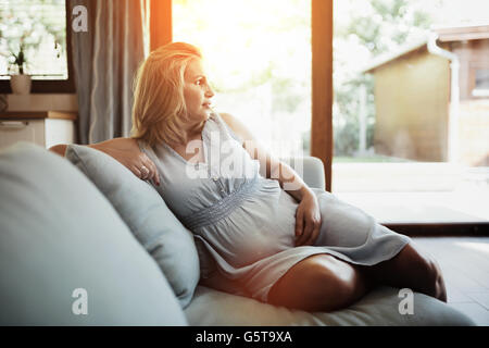 Schöne schwangere Frau ruht auf sofa Stockfoto