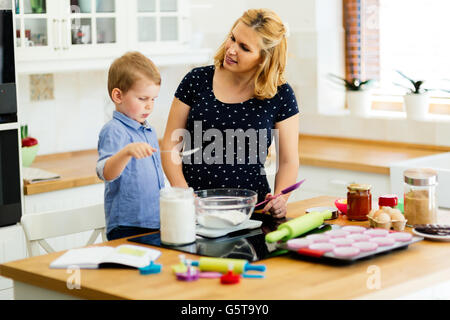 Kind hilft Mutter bereiten Sie Muffins in Küche Stockfoto