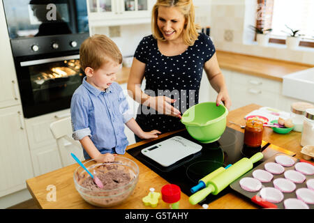 Kind hilft Mutter bereiten Sie Muffins in Küche Stockfoto