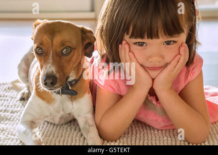 Ein Kleinkind Mädchen sitzt mit ihrem Haustier süßer Welpe Stockfoto