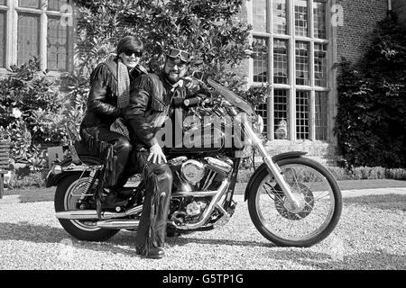 Der Millionär Peter de Savary und seine Frau Lana ziehen Motorradleder an, um mit ihrer Harley-Davidson FXR Super Glide den Ausritt von ihrem historischen Landsitz Littlecote House in der Nähe von Hungerford zu führen. Stockfoto