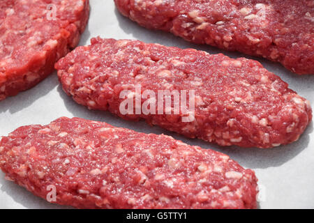 Rohes, rotes Fleisch-Burger, Kebab oder Patty Schnitzel von gehacktem Rindfleisch, Lamm, Schwein auf weißes Pergamentpapier bereit für das Kochen Stockfoto