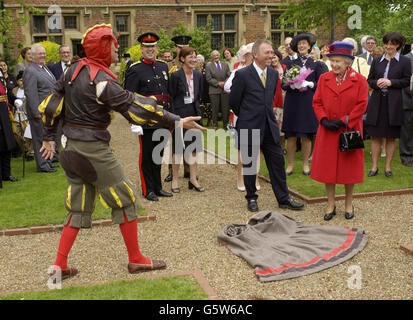 Königin Elizabeth II. Wird eingeladen, während ihres Golden Jubilee-Besuches in East London auf einem Kap zu treten, das ihr ein elisabethischer Narr alias Peet Cooper im Eastbury Manor House zu Füßen wirft. Stockfoto