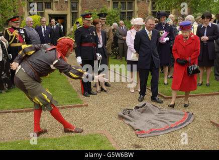 Die britische Königin Elizabeth II. Wird eingeladen, während ihres Golden Jubilee-Besuches in East London auf einem Kap zu treten, das ihr ein elisabethischer Narr alias Peet Cooper im Eastbury Manor House zu Füßen wirft. Stockfoto
