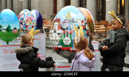 Eine Gruppe junger Mädchen studiert ein bunt bemaltes riesiges Osterei, Das ist eines von 100, die von heute bis zum 1. April im Rahmen der Lindt Big Egg Hunt zur Unterstützung der Aktion für Kinder Charity in Covent Garden im Zentrum von London in Städten im ganzen Land versteckt werden. Stockfoto