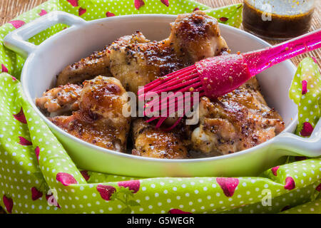 Gebratene Hähnchenflügel in weiße Auflaufform. Mit Sauce aus Senf, Honig und Sojasauce gekocht. Stockfoto