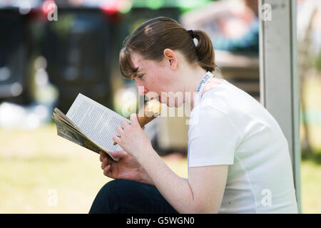 Eine junge Frau genießen ein Eis zu essen und ein Buch lesen in der warmen Sommersonne bei Hay Festival für Literatur und Kunst, Heu auf Wye, Powys, Wales UK, Sonntag, 5. Juni 2016 Stockfoto