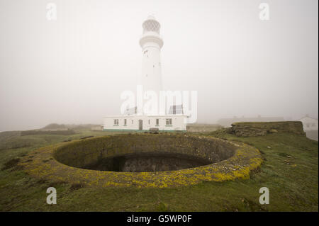 Ein allgemeiner Blick auf den Flat Holm Lighthouse, der 30 m (98 ft) hoch und 50 m (160 ft) über dem mittleren Hochwasser auf Flat Holm Island im Bristol Channel steht. Sie verfügt über eine 100-Watt-Lampe, die alle zehn Sekunden weiß und rot blinkt und eine Reichweite von bis zu 56 km (30 nmi) hat. Im Vordergrund befindet sich eine viktorianische Moncrieff-Grube, die Teil der Lighthouse Battery auf Flat Holm Island ist. Flat Holm Battery ist eine Reihe von Geschützstellungen auf der Insel, die gebaut wurden, um Bristol und Cardiff über den Kanal zu schützen und onced untergebracht ein Rifle Muzzel geladen 7-Zoll-7-Tonnen-Kanone, die in der Lage war zu vereißeln Stockfoto