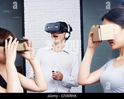 drei junge Asiaten tragen verschiedene Arten von virtueller Realität (VR) Brille. Stockfoto