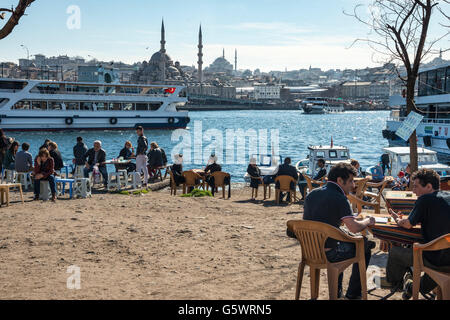 Cafés auf Karakoy Uferpromenade, Blick über das Goldene Horn auf die Yeni-Moschee auf Eminönü und die Skyline von Istanbul. Istanbu Stockfoto