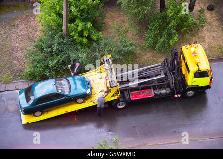 Laden kaputtes Auto auf einen Abschleppwagen auf einer Straße. Luftbild Stockfoto