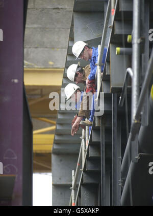 Arbeiter auf der Werft Alstom Chantiers de L'Atlantique in Saint Nazaire, Bretagne, Frankreich, beobachten, wie die Kielverlegung auf der Queen Mary 2 stattfindet. * die Zeremonie markiert den symbolischen Beginn des Baus des 1.132 Fuß langen Schiffes, das 200 Fuß über der Wasserlinie ragen wird, die am 14. Januar 2004 die erste Reise von Southampton nach Fort Lauderdale machen wird. Stockfoto