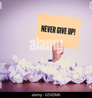 HAND, DIE GELBEN PAPIER MIT NEVER GIVE UP! KONZEPT Stockfoto