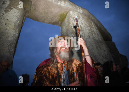 Ein lächelnder Druide mit Personal kommt unter den Steinen in Stonehenge, um die Sommersonnenwende zu feiern Stockfoto