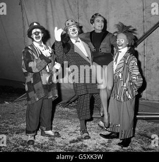 In einem Kostüm mit Netzstrumpfhose erhält die Hollywood-Schauspielerin Joan Crawford die Unterstützung von einem oder zwei der Clowns im Zirkus von Billy Smart, als sie als Ringmeisterin für eine Wohltätigkeitsveranstaltung unter dem großen Dach von Blackheath tätig war. Stockfoto