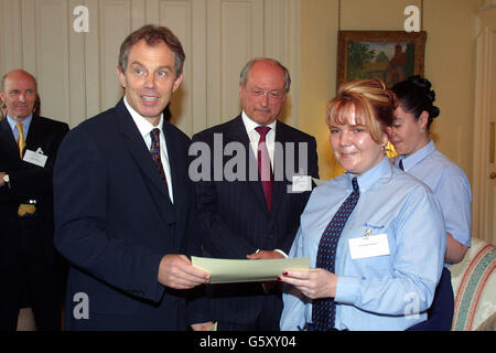 Der britische Premierminister Tony Blair überreicht Amanda Ephgrave aus London ein Zertifikat, während Roy Gardner, Cheif Excecutive von Centrica PLC, bei einem Empfang in der Downing Street für alleinerziehende Eltern, die wieder zur Arbeit kommen, zuschaut. * Gewerkschaften und Wahlkampfgruppen begrüßten heute Abend eine neue Regierungskampagne, um mehr einallein erziehenden Eltern und behinderten Menschen zu helfen, Arbeit als Teil weiterer Reformen des Wohlfahrtsstaates zu finden. Der Premierminister sprach von einem neuen Vertrag zwischen Bürgern und Gesellschaft, als er Pläne ankündigte, das Land näher an Vollbeschäftigung zu bringen. Stockfoto