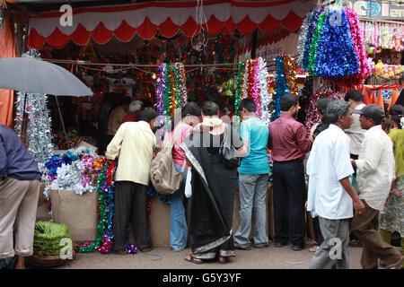 Menschen in Indien verschiedene Rituale und Dekoration Gegenstände während eines Festes in einem Streetside-Shop einkaufen. Stockfoto