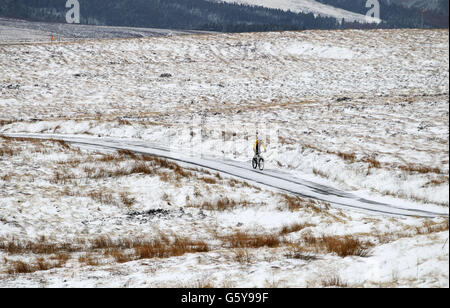 Ein Radfahrer macht seinen Weg entlang einer verschneiten Strecke in der Nähe von Ladmanlow, Derbyshire, als eine Rückkehr von eisigen Temperaturen und Schnee an diesem Morgen wird weitere Verzögerung Frühling Wetter für Großbritannien. Stockfoto