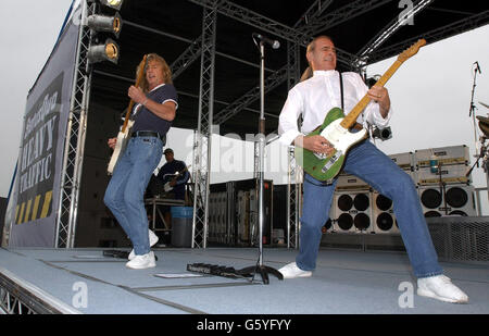 Rick Parfitt (links) und Francis Rossi von Status Quo spielen für Fans und Segler an Bord der HMS Ark Royal in Portsmouth. Die Band inszenierte das Konzert, um ihr neues Album Heavy Traffic zu promoten. Stockfoto