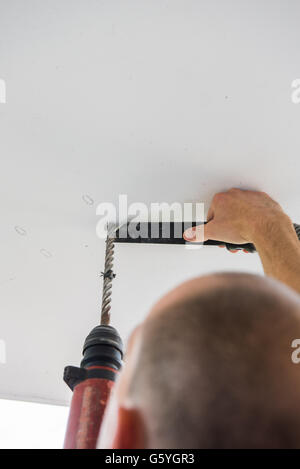 Man bohrt Löcher in Betondecke mit Bohrmaschine Stockfoto