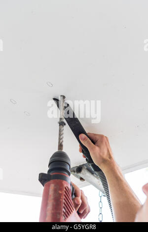 Man bohrt Löcher in Betondecke mit Bohrmaschine Stockfoto