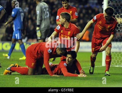 Liverpools Luis Suarez (Boden) feiert mit den Teamkollegen Glen Johnson (links), Steven Gerrard (Mitte) und Joe Allen (rechts), nachdem er seinen Hattrick und das vierte Tor des Spiels für seine Mannschaft während des Barclays Premier League-Spiels im DW-Stadion Wigan erzielt hat. Stockfoto