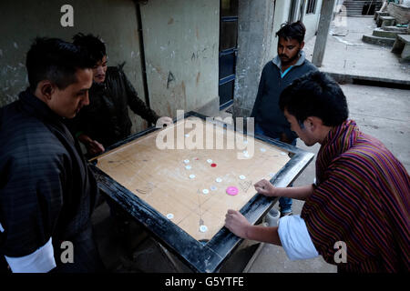 Einheimische Männer spielen das traditionelle Brettspiel Carrom in der Straße von Thimphu in Bhutan Stockfoto