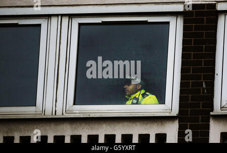 Ein Polizist schaut aus einem Wohnblock am St Andrew's Drive in Glasgow, nachdem ein vierjähriger Junge nach einem Sturz aus einem Fenster gestorben ist. Stockfoto