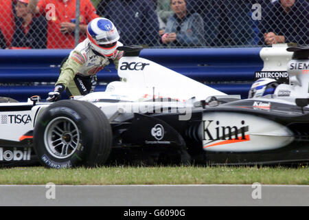 Als David Coulthard in einem McLaren auf die Curcuit kommt, stockt Lucky Strike-BARFAHRER Olivier Panis sein Auto ab und muss sein Auto etwa 300 Meter zurück in die Boxengasse schieben, bevor er den Motor wieder starten und vor dem Start seinen Platz im Startfeld einnehmen kann Der große Preis von Großbritannien. Stockfoto