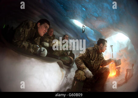 (Von links nach rechts) Marine William Corry von Royal Wootton Basset, Marine Dave Koumi aus London, Corporal Dan Holder von Horsham und Marine Greg Spencer aus London kochen Wasser aus Schnee in ihrem Schneeloch, das sie gebaut und in dem sie lagerten, während die Truppen an der Übungshurspring 2013 teilnehmen, Die sich auf das Überleben bei kaltem Wetter und das Kriegstraining für Royal Marines Commando-Reservisten in den Bergen in der Nähe von Porsanger Garrison bei Lakselv, Norwegen, konzentriert. Stockfoto