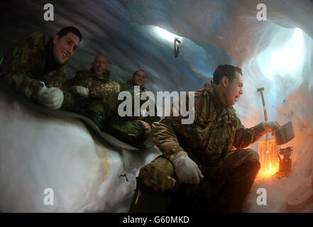 l-r Marine William Corry von Royal Wootton Basset, Marine Dave Koumi aus London, Corporal Dan Holder von Horsham und Marine Greg Spencer aus London kochen Wasser aus Schnee in ihrem Schneeloch sie gebaut und lagerten in während der Übung Haarspring 2013, die sich auf kaltes Wetter Überleben und Kriegstraining für konzentriert Royal Marines Commando Reservisten in den Bergen bei Porsanger Garrison in der Nähe von Lakselv, Norwegen. Stockfoto