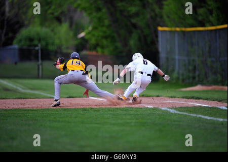 Auf was schien, einen Lauf zu sein scoring Single, ein Geschlagener Eierteig/Base Runner springt für die Tasche als der erste Basisspieler erstreckt sich über eine werfen. USA. Stockfoto