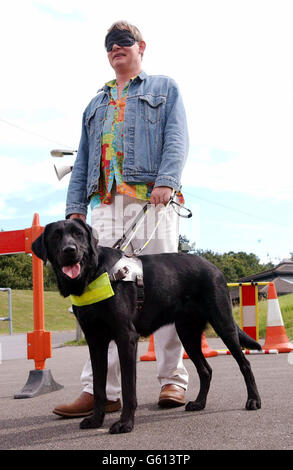 Schauspieler Martin Clunes wird von Buster, einem 18 Monate alten labrador-Cross-Retriever, um einen Hindernisparcours im Ausbildungszentrum Guide Dogs for the Blind Association in Woodford, Essex geführt. *Martin, die Stimme des TV-Zeichentrickhundes Merlin, besuchte das Zentrum, um sich einem echten Führerhund namens Merlin anzuschließen, der ebenfalls im Zentrum ausgebildet wird. Stockfoto