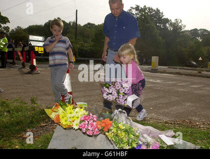 Eine Familie hinterlässt Blumen zu Ehren von Milly Dowler am Straßenblock der Polizei in der Nähe von Yateley Heath, Minley, in Hampshire, wo die Überreste von Milly gefunden wurden, die angeblich Milly sind. Mehr als 100 spezialisierte Suchbeamte kämmten den Ort. *... auf der Suche nach Hinweisen zum Mörder des Teenagers. Stockfoto