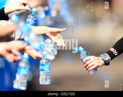 Läufer helfen sich beim Virgin London Marathon in London zu wässern. Stockfoto