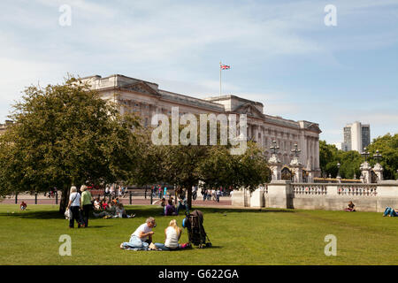 Touristen, die Ruhe auf dem Rasen vor Buckingham Palace, London, England, Vereinigtes Königreich, Europa Stockfoto