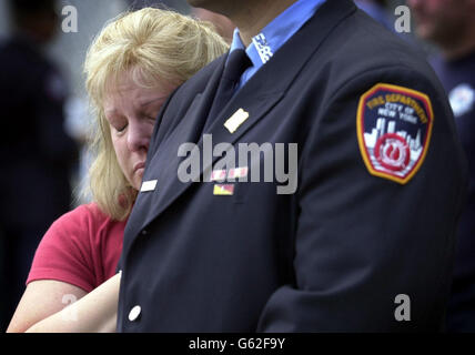 Eine Dame hängt an ihrem Mann, einem New Yorker Feuerwehrmann, der zum ersten Jahrestag der Terroranschläge auf das World Trade Center anwesend ist. Stockfoto