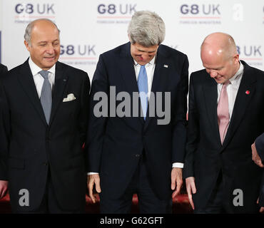 Der französische Außenminister Laurent Fabius (links) schaut während eines Gruppenfotos beim G8-Außenministertreffen im Lancaster House in London auf die Positionen des US-Außenministers John Kerry und des Außenministers William Hague (rechts). Stockfoto