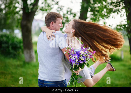 schöne Frau mit langen Haaren und ein glücklicher Mann umarmt im Feld Stockfoto