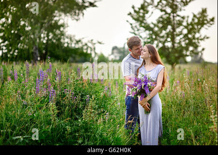 schöne Frau mit langen Haaren und ein glücklicher Mann umarmt im Feld Stockfoto