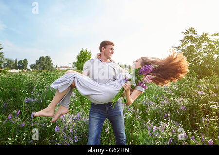 Glückliche Liebe Mann, eine Frau auf seine Arme im Feld Stockfoto