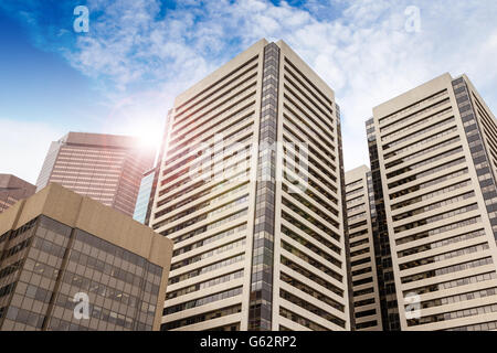 Prost Blick auf Bürogebäude in der Innenstadt von Calgary mit Blendenfleck vor einem blauen und bewölkten Himmel. Stockfoto