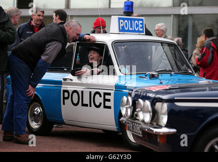Der Autoenthusiast Robert Napier von Newmains spricht mit der Polizeibeamten Carrie-Ann McNab, als sie in einem Hillman Imp Polizeiwagen sitzt, während sie sich darauf vorbereiten, den Standort der ehemaligen Fabrik in Linwood mit einem Konvoi zu verlassen, um den 50. Jahrestag des ersten Hillman Imp Autos zu begehen, das am hergestellt wurde Autofabrik Rootes. Stockfoto