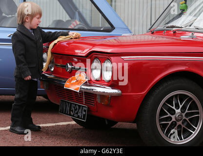 Autoenthusiasten der vierjährige Zach Stuart poliert einen Hillman Imp, als die Autos sich vorbereiten, mit dem Konvoi den Standort des ehemaligen Werks in Linwood zu verlassen, um den 50. Jahrestag des ersten Hillman Imp-Autos zu begehen, das im Autowerk Rootes hergestellt wurde. Stockfoto