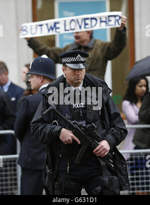 Ein bewaffneter Polizist steht Wache, während Zuschauer beginnen, die Beerdigungsroute vor dem Trauerdienst von Baroness Thatcher in der St Paul's Cathedral im Zentrum von London zu säumen. Stockfoto