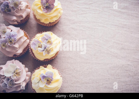 Lila und gelb-Cupcakes mit essbaren Blumen textfreiraum Tonen Hintergrund gezuckert Stockfoto